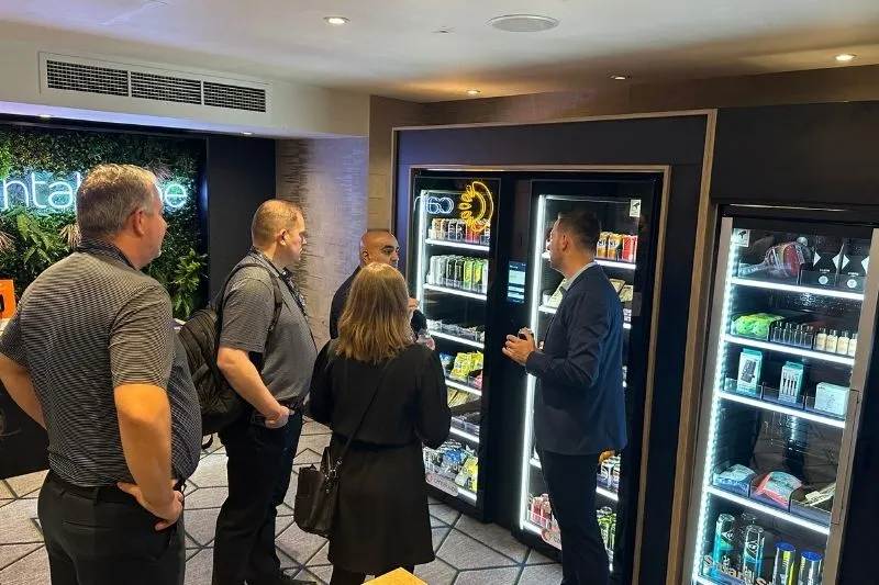 A Cantaloupe employee explains the Smart Store to three conference attendees.